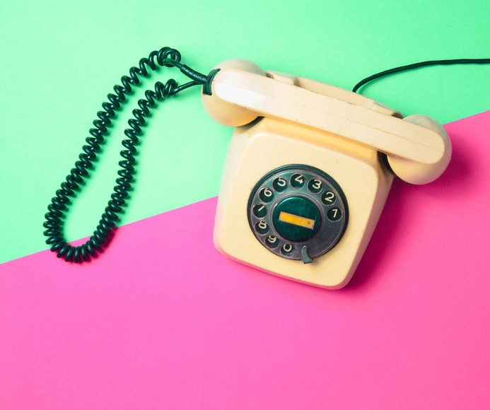 Retro phone on a multi-colored table. Pop colors. Communication 80s. Flat lay.