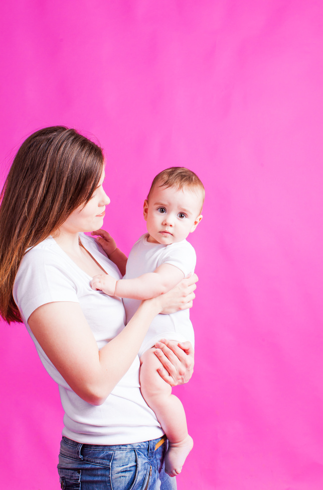 Young Mother Holding Her Baby, on a Pink Background