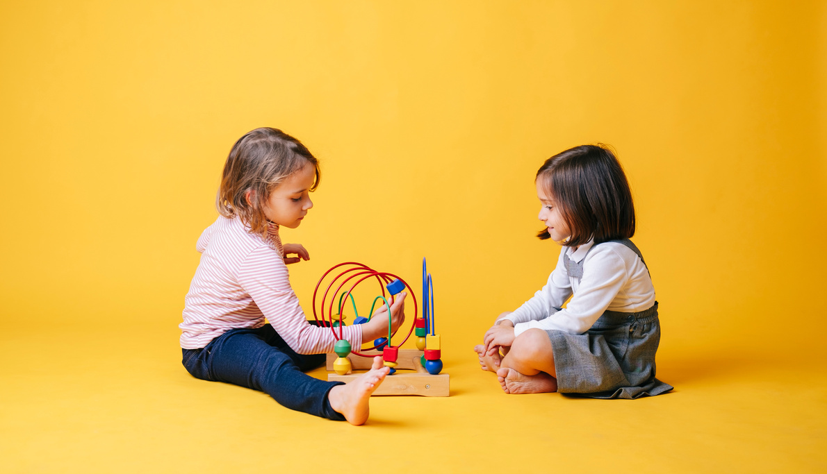 Two Kids with Toys on Yellow Background